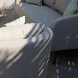 Light grey outdoor sofa set with green patterned cushions in sunlight