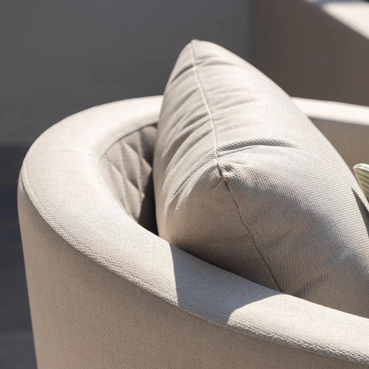 Closeup of beige fabric armchair with curved back and plush cushion