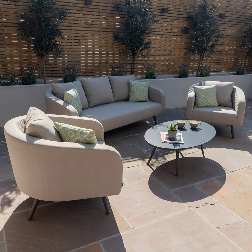 Outdoor sofa set with beige cushions, matching armchairs and a round coffee table on a patio