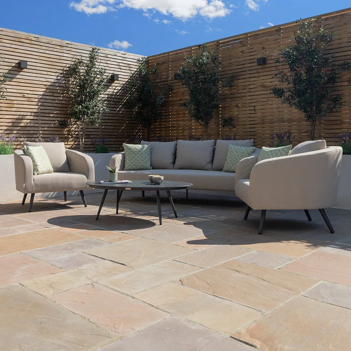 Outdoor garden sofa set with grey cushions, matching armchairs and coffee table on patio