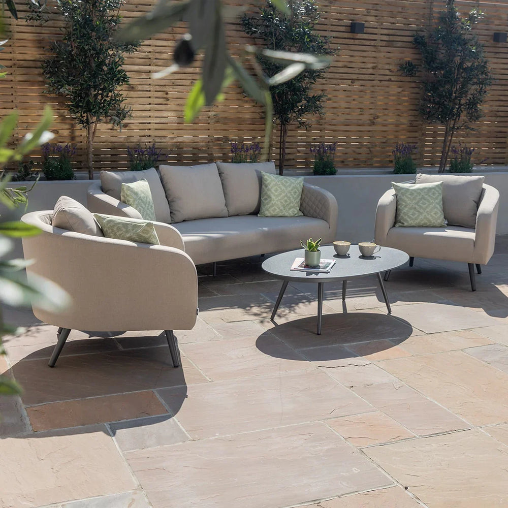 Beige garden sofa set with matching armchairs and round coffee table on stone patio