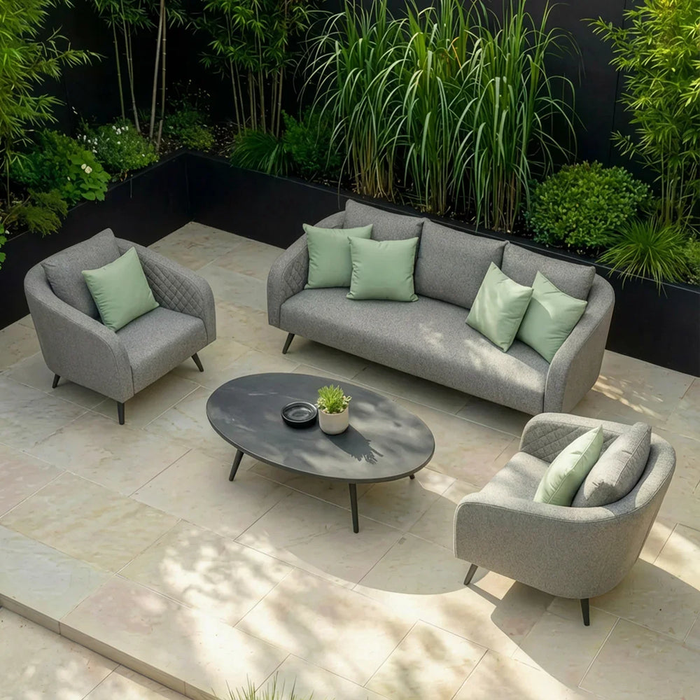 Grey outdoor sofa set with armchairs, light green cushions, and oval table on patio tiles