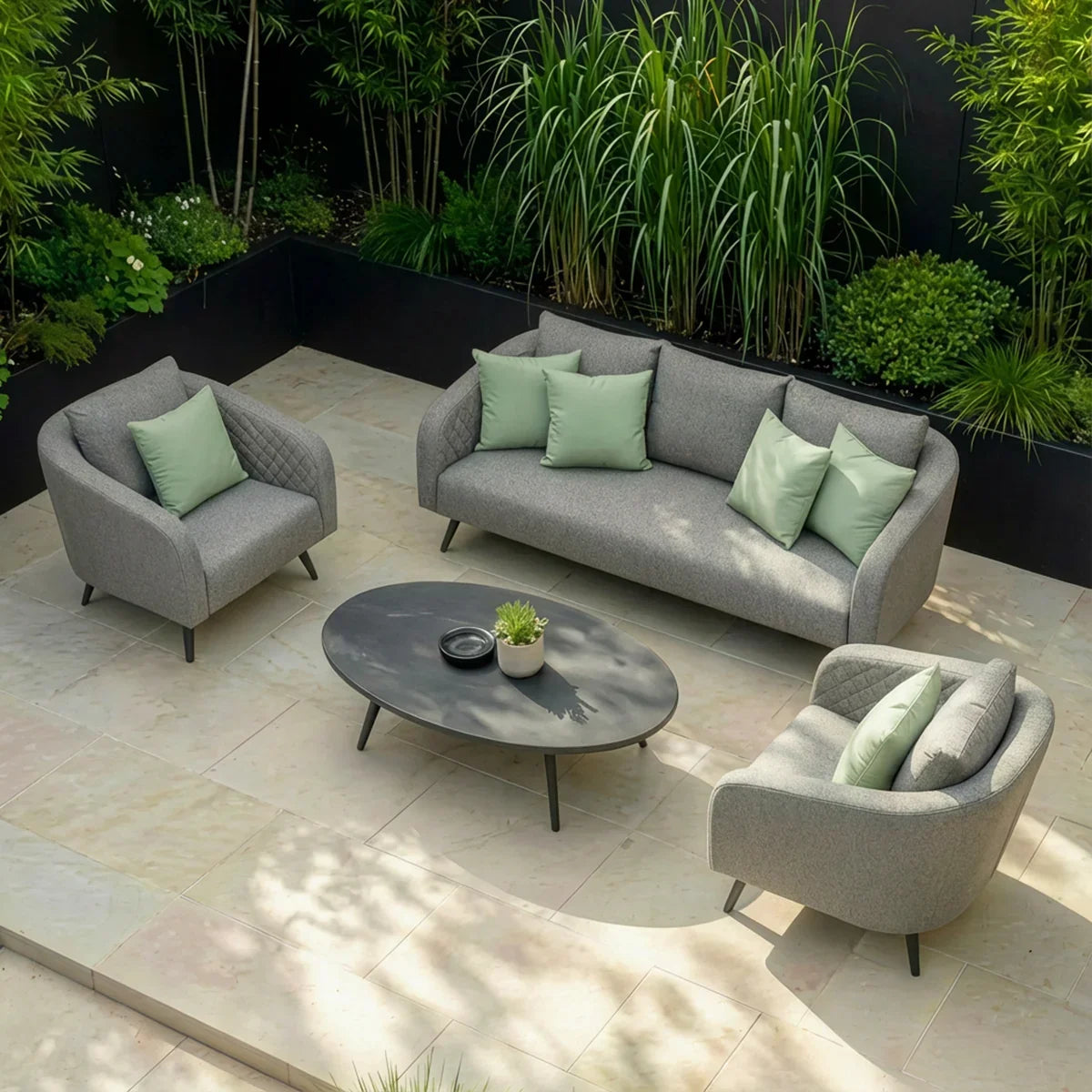Grey outdoor sofa set with armchairs, light green cushions, and oval table on patio tiles