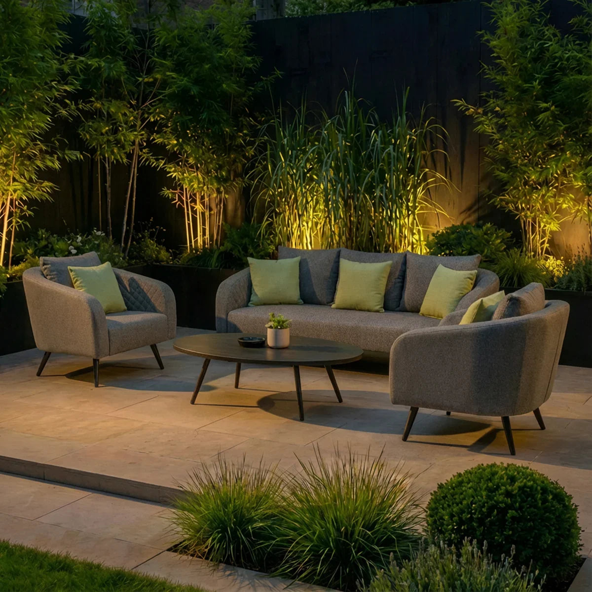 Outdoor sofa set with grey fabric armchairs, cushions and coffee table on patio, evening setting