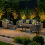 Outdoor sofa set with grey fabric armchairs, cushions and coffee table on patio, evening setting