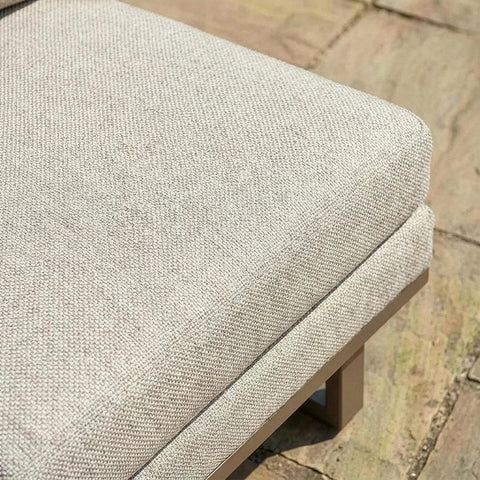Close-up of beige outdoor sofa cushion on wooden frame with patio paving