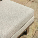 Close-up of beige outdoor sofa cushion on wooden frame with patio paving