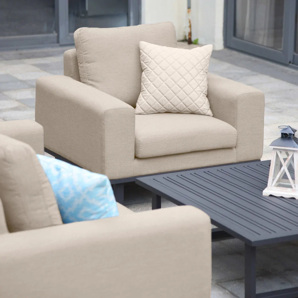 Beige outdoor armchair set with quilted cushion beside black slatted coffee table on patio