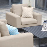 Beige outdoor armchair set with quilted cushion beside black slatted coffee table on patio