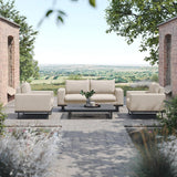 Cream outdoor sofa set with armchairs and coffee table on stone patio, countryside view