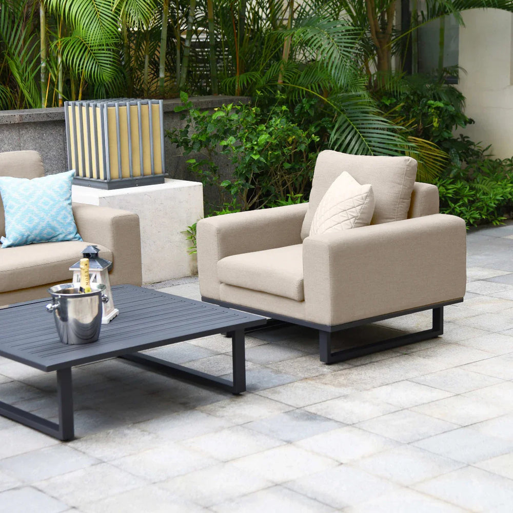 Beige outdoor armchair with cushion and black metal coffee table on patio with plants
