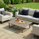 Outdoor garden sofa set with grey cushions and slatted coffee table on stone patio