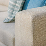 Beige fabric sofa armrest close-up with blue and striped cushions