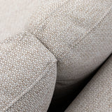 Close-up of beige fabric sofa armrest with textured upholstery and visible stitching