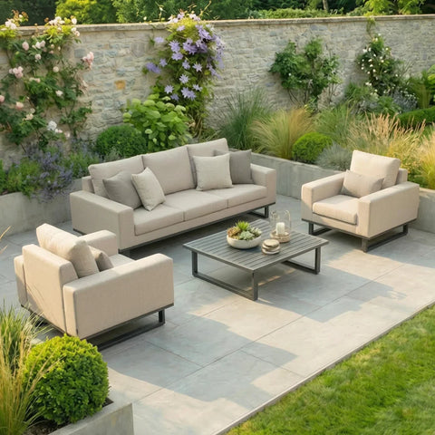 Beige outdoor sofa set with armchairs and coffee table on a stone patio in a garden