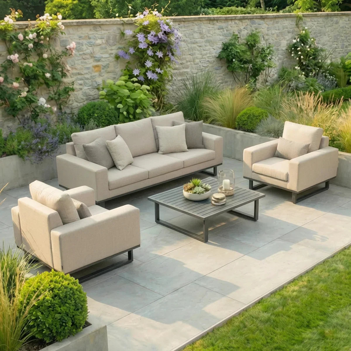 Beige outdoor sofa set with armchairs and coffee table on a stone patio in a garden