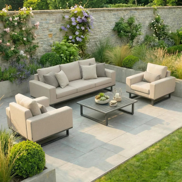 Beige outdoor sofa set with armchairs and coffee table on a stone patio in a garden