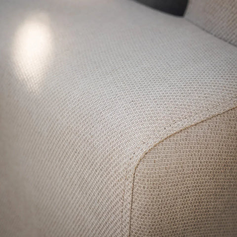 Close-up of beige fabric sofa arm with textured upholstery detail
