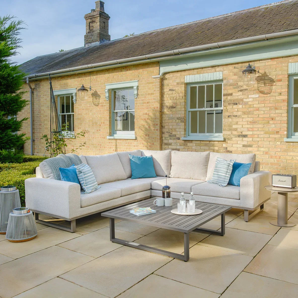 Light grey outdoor corner sofa set with blue cushions and coffee table on patio