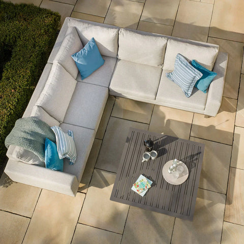 Light grey outdoor corner sofa set with blue cushions and coffee table on patio tiles