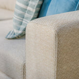 Beige fabric sofa arm with textured weave and striped cushion detail