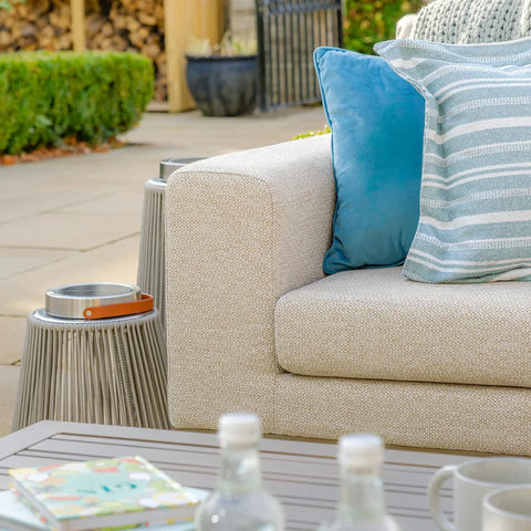 Outdoor fabric sofa with blue and striped cushions beside modern garden side table