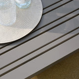 Close view of grey slatted garden table with textured glass and woven placemat
