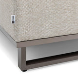 Beige woven outdoor sofa cushion on grey metal frame, corner close-up