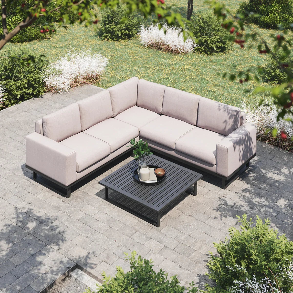 Outdoor corner sofa with beige cushions and black coffee table on stone patio