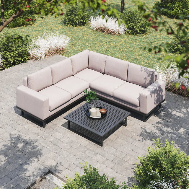 Outdoor corner sofa with beige cushions and black coffee table on stone patio