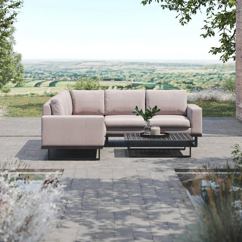Light beige outdoor corner sofa with black coffee table on paved patio overlooking countryside