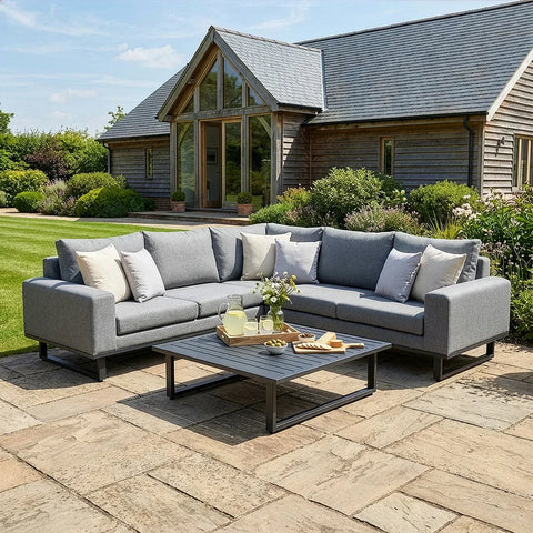Grey outdoor corner sofa set with cushions and coffee table on stone patio