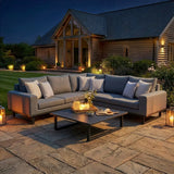 Grey outdoor corner sofa set with cushions and coffee table on stone patio at dusk