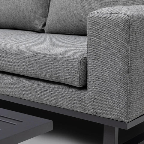 Close-up of grey fabric sofa with metal base and square armrest