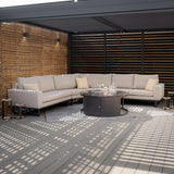Beige outdoor corner sofa set with cushions and round fire pit table on covered decking