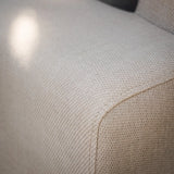 Close-up of beige fabric sofa arm with textured upholstery detail