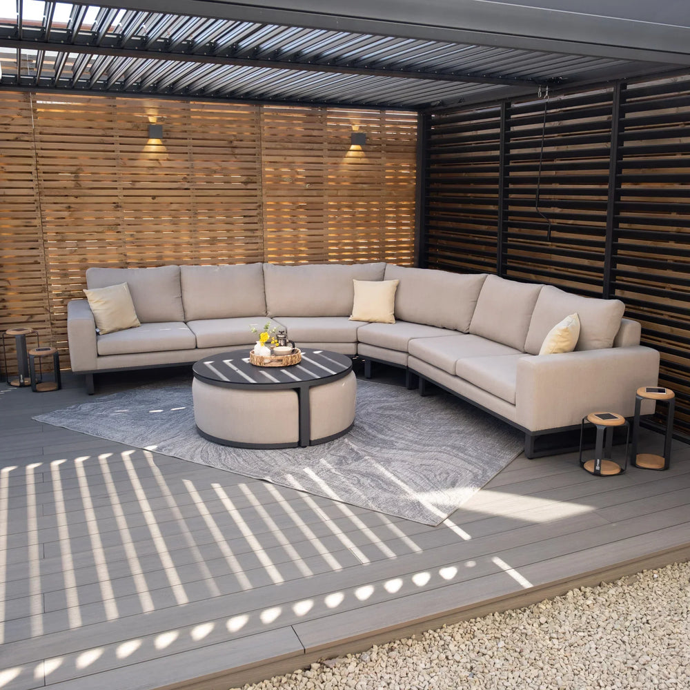 Beige outdoor corner sofa set with round coffee table on decked patio under pergola