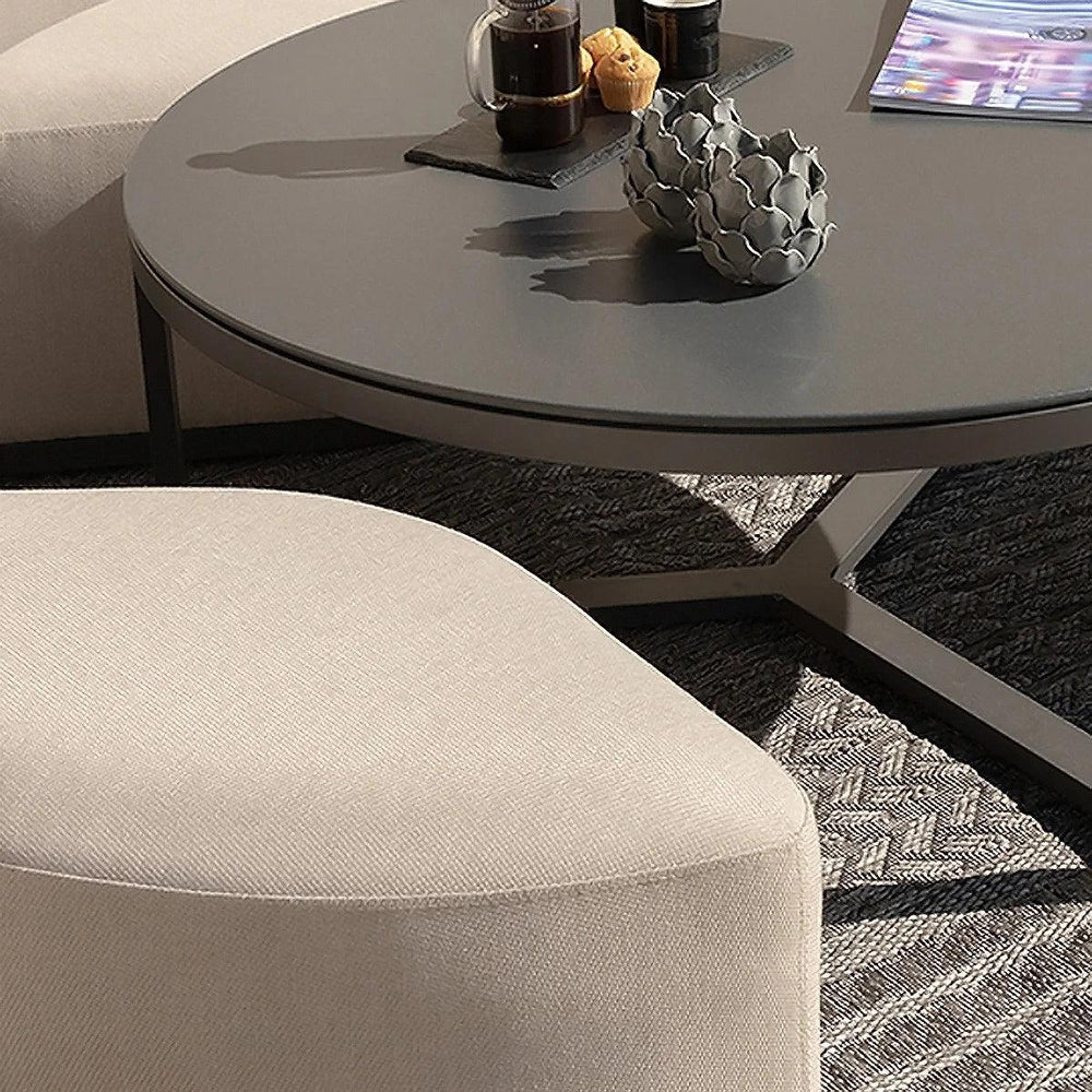 Round grey coffee table with black tray, two drinks, muffin, and beige upholstered seat
