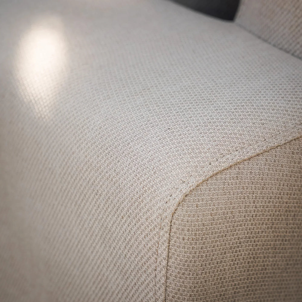Close-up of beige fabric sofa armrest showing textured upholstery detail