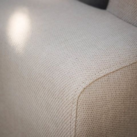Close-up of beige fabric sofa armrest showing textured upholstery detail