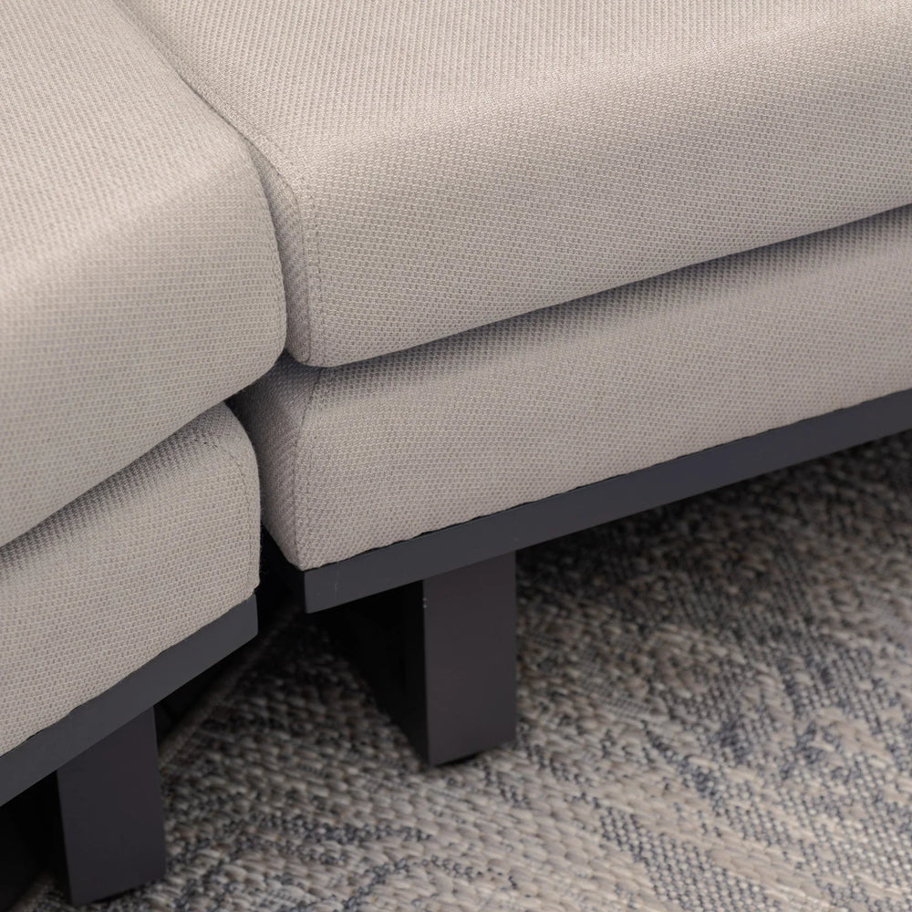 Closeup of grey fabric sofa corner with black legs on textured rug