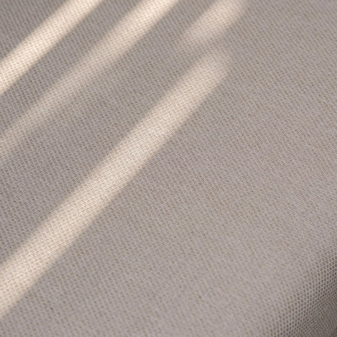 Beige fabric upholstery with subtle textured weave and natural sunlight shadows