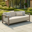 Outdoor two-seater garden sofa with light beige cushions on modern patio