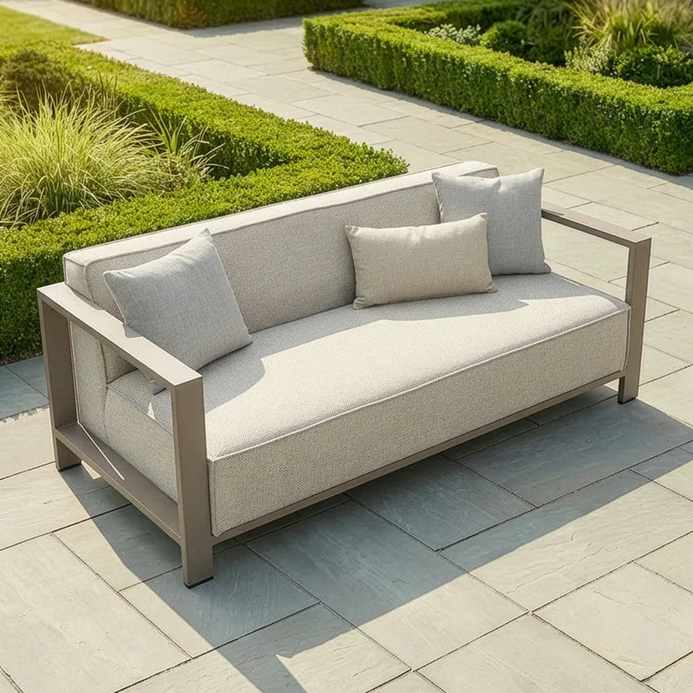 Outdoor beige garden sofa with metal arms and cushions on stone patio