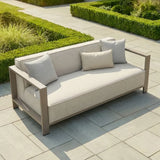 Outdoor beige garden sofa with metal arms and cushions on stone patio