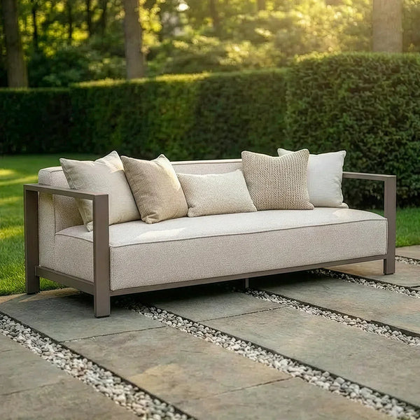 Beige outdoor sofa with metal frame and neutral cushions on stone patio in garden setting