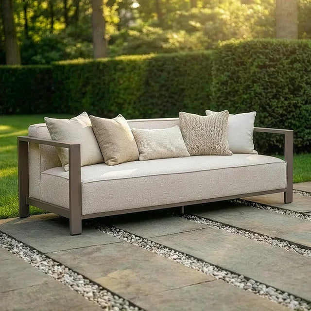 Beige outdoor sofa with metal frame and neutral cushions on stone patio in garden setting