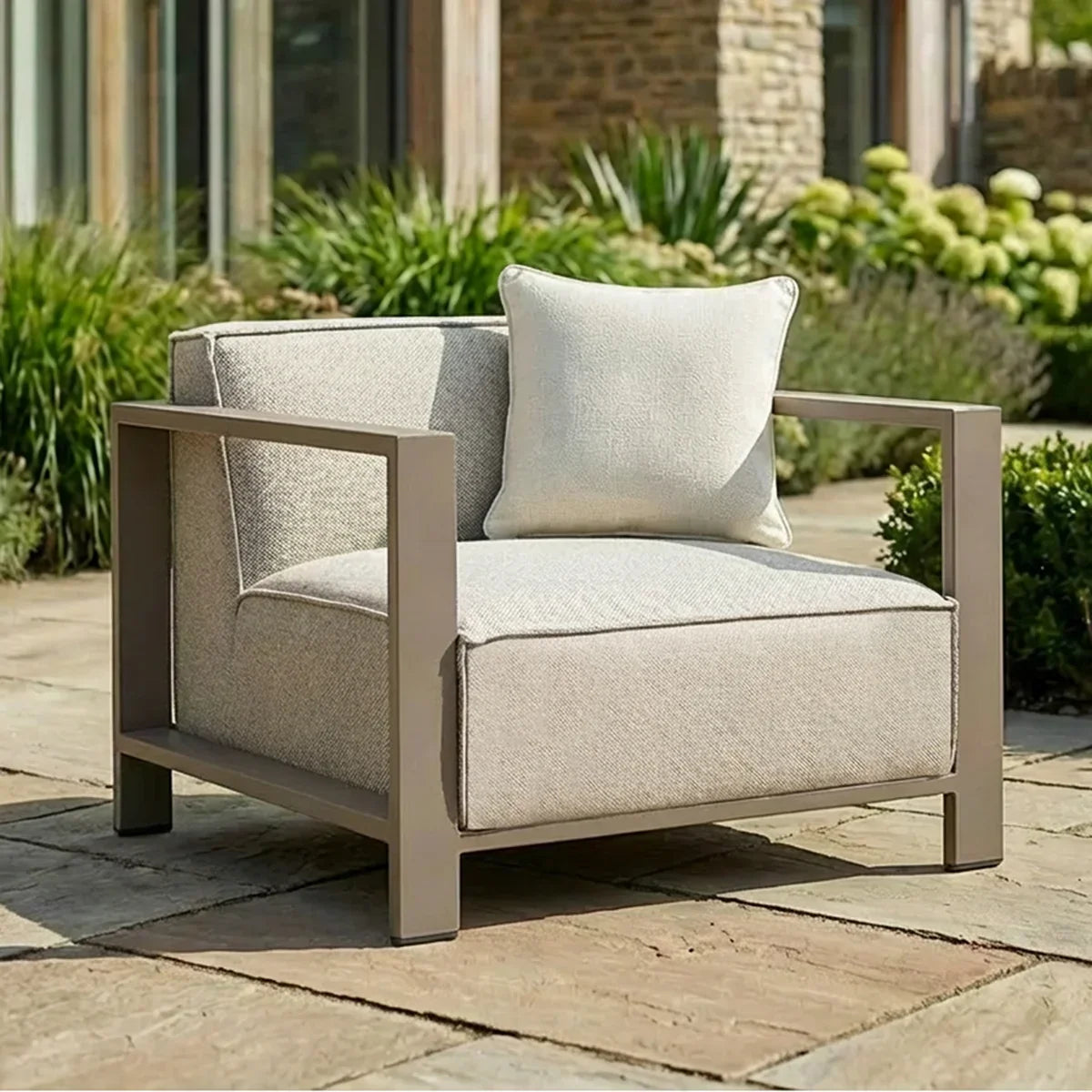Modern outdoor armchair with beige cushions and metal frame on stone patio
