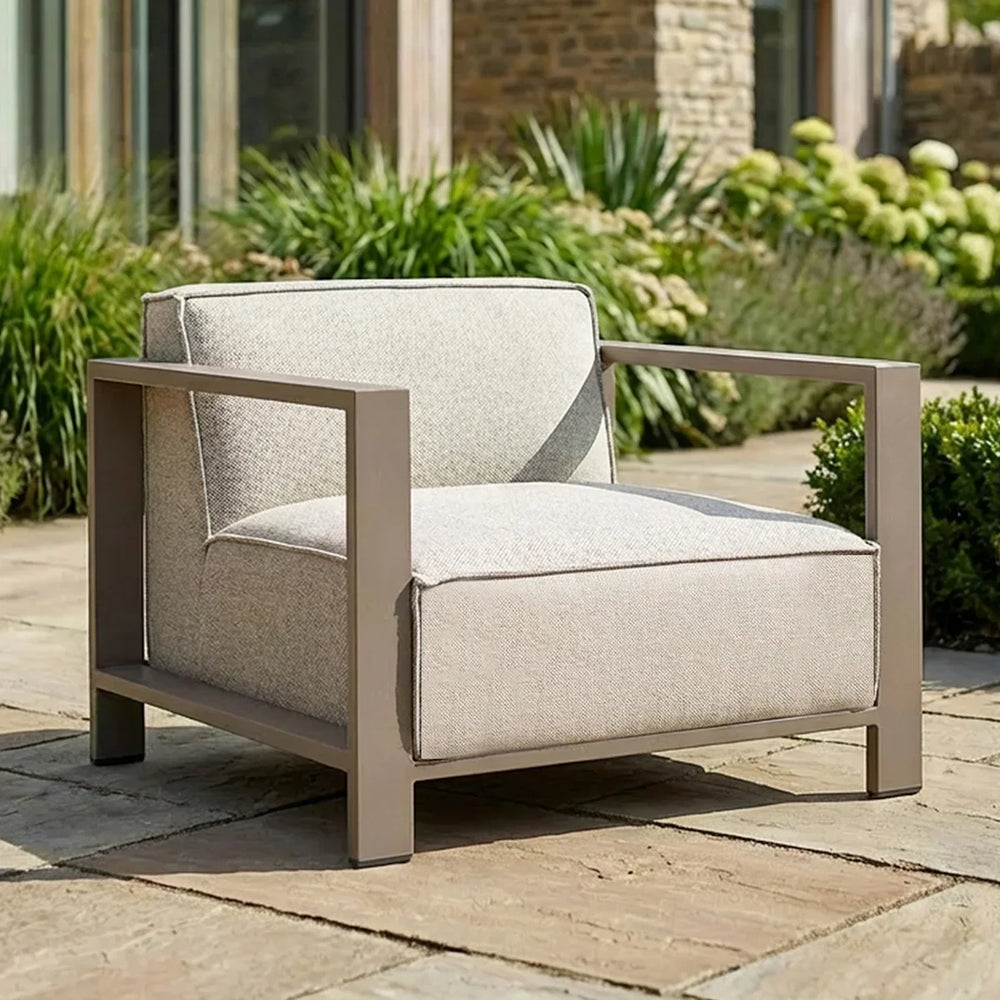 Beige outdoor armchair with metal frame and cushions on stone patio