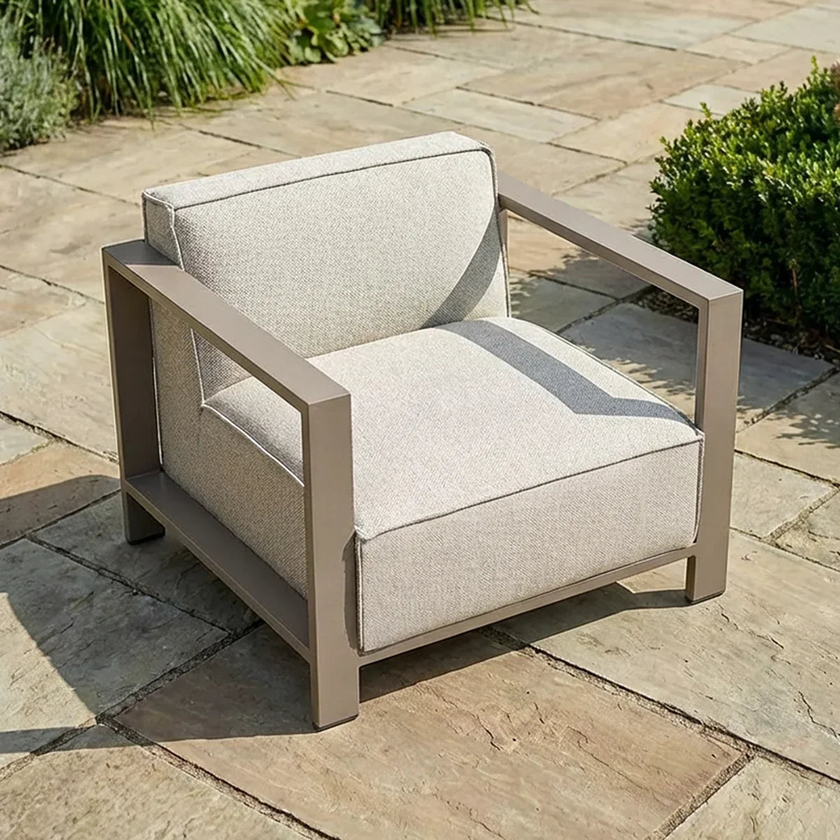 Beige outdoor armchair with metal frame on a stone patio